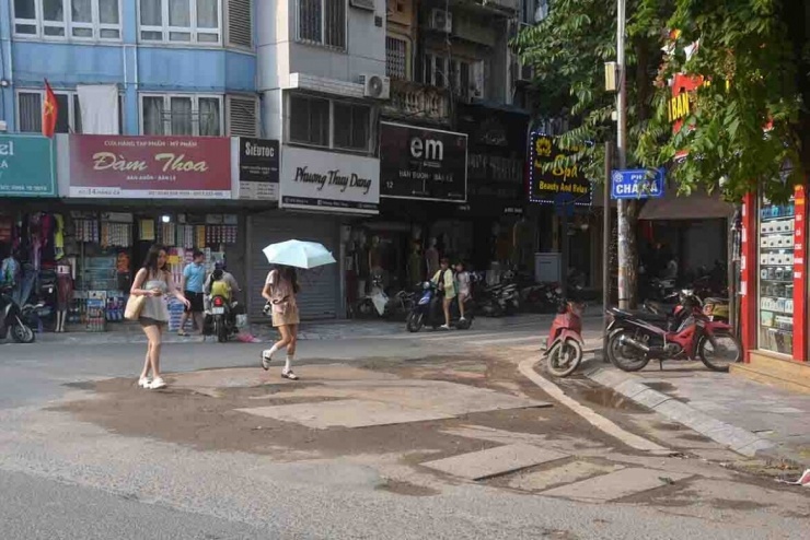 Người dân liên tục tưới nước trước cửa nhà để giảm bụi.