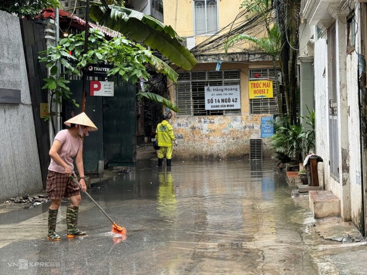 9h sáng 28/7, ngõ 42 Giang Văn Minh, phường Ba Đình vẫn ngập hơn 20 cm sau hai ngày mưa lớn, công nhân thoát nước phải túc trực mở nắp ga vớt rác. Ảnh: Nga Thanh
