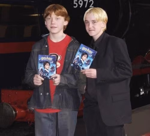 Rupert Grint và Tom Felton cầm trên tay DVD Harry Potter và Hòn Đá Phù Thủy.