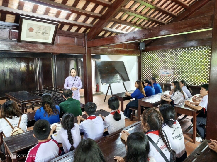 Chị Nguyễn Thị Thu Nga, cán bộ thuyết minh với đoàn khách TP HCM về lịch sử của trường. Khách đến đây được trải nghiệm làm học sinh ngồi trong ngôi trường mà thầy giáo Nguyễn Tất Thành từng dạy học.