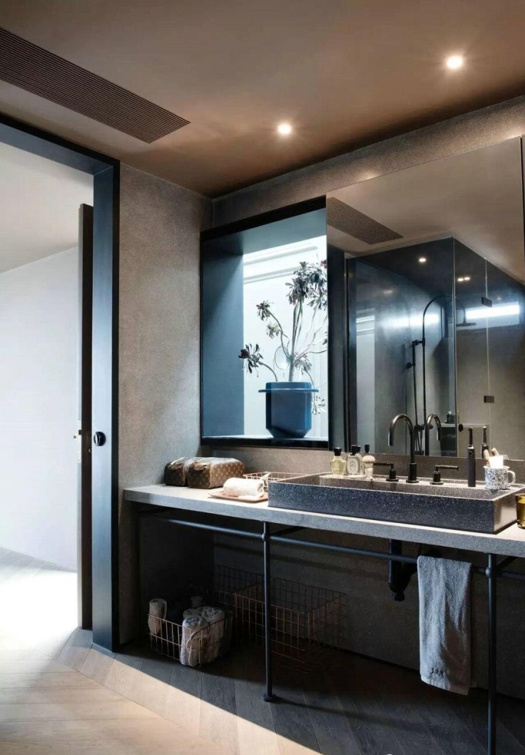 Phòng tắm trong phòng ngủ dùng gạch terrazzo kết hợp phụ kiện kim loại. Một ô kính mở về hành lang giúp đưa thêm ánh sáng vào bên trong. Hệ tủ gương vừa dùng lưu trữ, vừa có thể trượt che cửa kính khi cần tăng riêng tư.