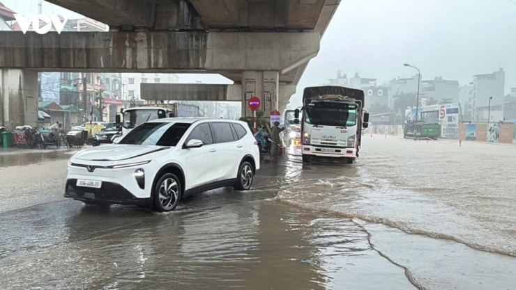 Mặt đường Quốc lộ 6 chìm trong nước sau mưa lớn, nhiều phương tiện phải tìm cách vượt qua, khiến việc lưu thông bị ảnh hưởng.