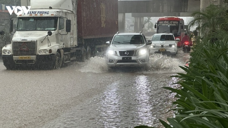 Nước ngập khiến mặt đường bị thu hẹp, một số phương tiện phải di chuyển sang phần đường ngược chiều để tránh khu vực ngập sâu.