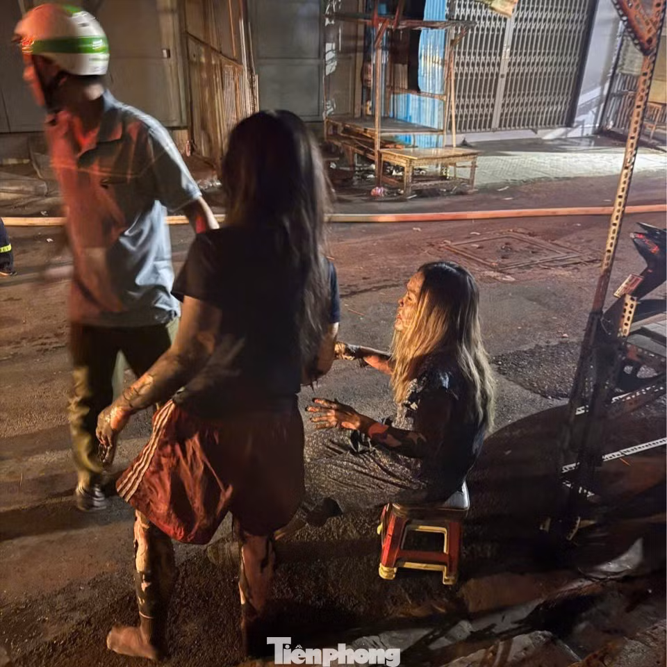 Hai mẹ con được người dân hỗ trợ đưa xuống đất sau khi nhảy từ sân thượng sang mái nhà bên cạnh. Ảnh: Nguyễn Tiến