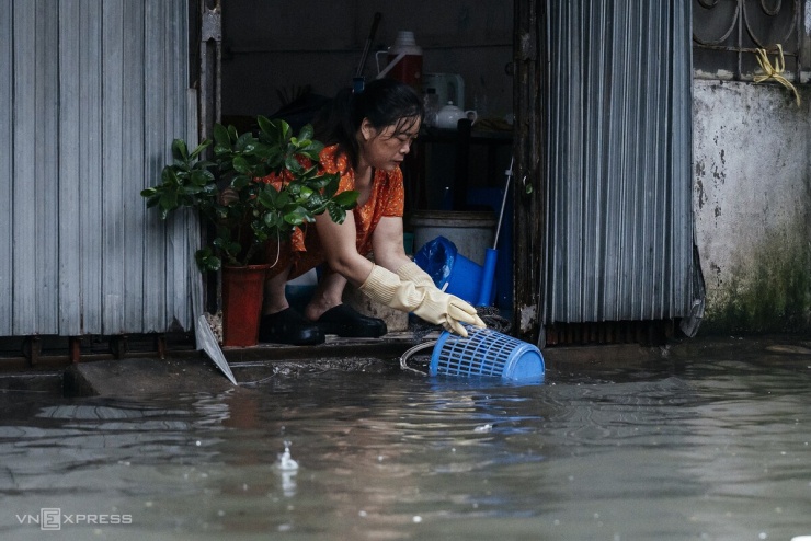 Tranh thủ nước ngập, người phụ nữ mang đồ đạc ra kỳ cọ cho sạch. Ảnh: Tùng Đinh