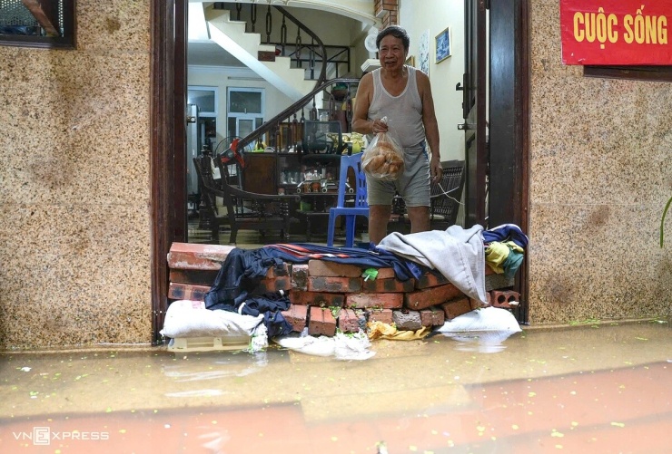 Tại ngõ 39 Tứ Liên, phường Hồng Hà, hàng trăm hộ dân bị nước tràn vào nhà, có nơi ngập sâu tới 1,2 m. Nhiều gia đình không thể lội ra ngoài mua thực phẩm, phải nhờ hàng xóm tiếp tế đồ ăn. Một số hộ dựng vách ngăn nước nhưng vẫn không thể ngăn dòng nước tràn vào. Ảnh: Huy Mạnh