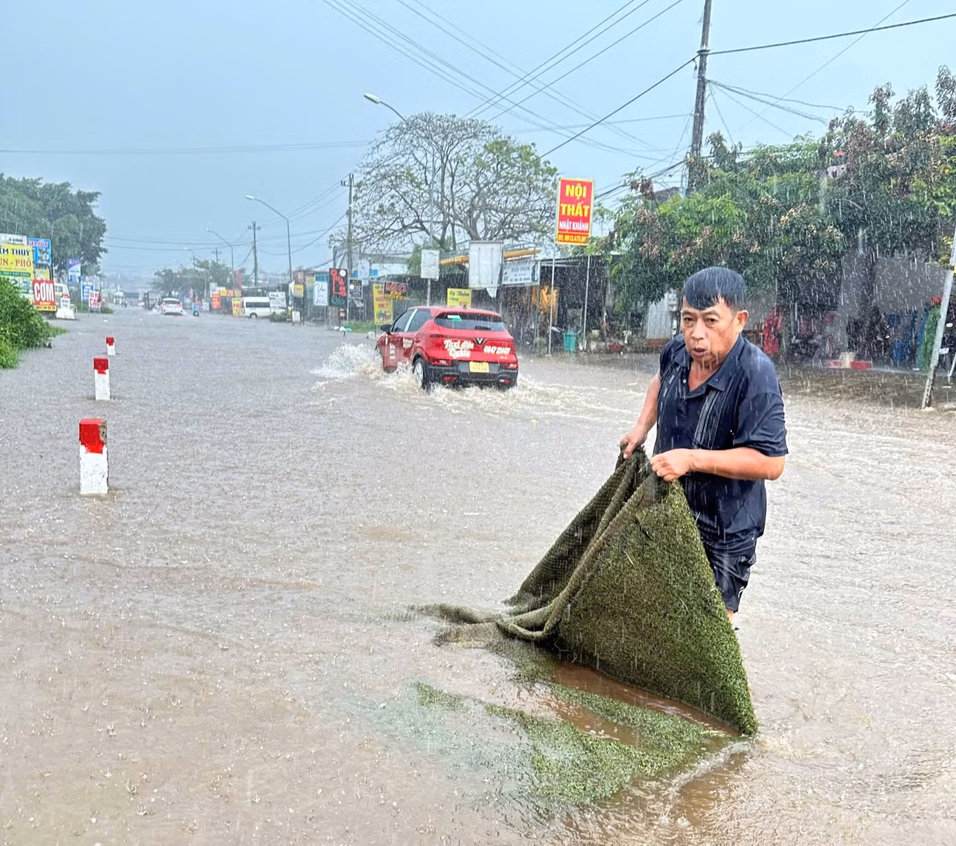 Ông Trần Văn Long kéo các vật cản nơi miệng cống giữa trời mưa.