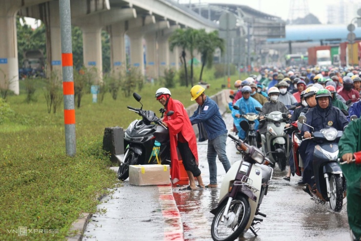 Người đàn ông chở hàng bị ngã gần cầu Rạch Chiếc, sau đó được người đi đường hỗ trợ đỡ dậy.