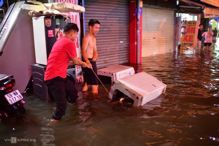 Người dân dùng dây giữ, kéo những chiếc máy giặt bị dòng nước cuốn trôi.