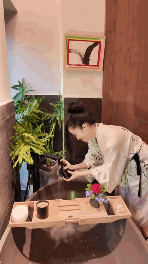 Đáng chú ý, phòng tắm cũng được chăm chút như một không gian thư giãn riêng. Cửa sổ lớn giúp căn phòng đón ánh sáng tự nhiên, kết hợp cây xanh và tranh trang trí, mang lại cảm giác nhẹ nhàng. Tuy nhiên, với những khu vực thường xuyên tiếp xúc với hơi nước, việc thông gió và kiểm soát độ ẩm vẫn là yếu tố quan trọng để hạn chế nấm mốc. Phụ Nữ Mới cho hay.