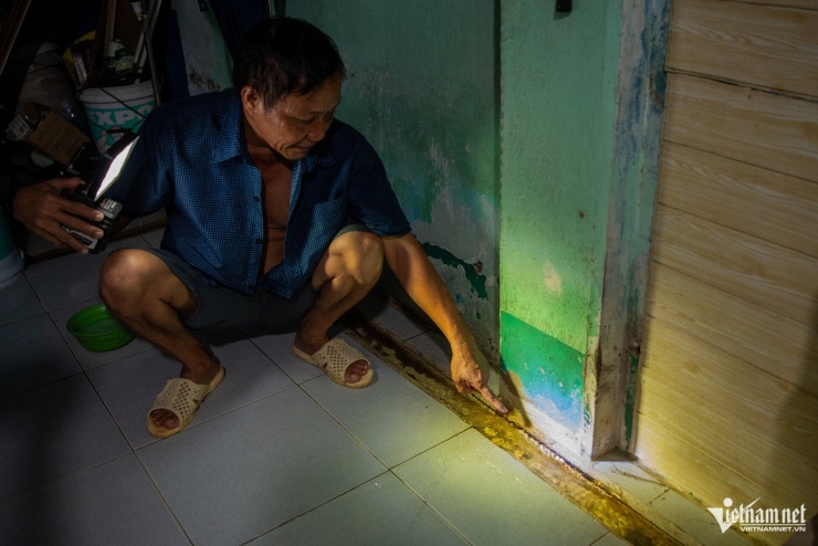 Để khắc phục tình trạng trên, ông tự thiết kế, đào rãnh xung quanh nhà để dẫn nước về vị trí đặt máy bơm, sau đó bơm ra ngoài. (Ảnh trái: ông Chung chỉ vào rãnh do ông tự đào, dài khoảng 4m). 