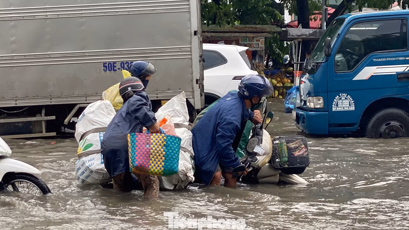 Người đi xe máy bị ngã và được người dân xung quanh đến giúp hỗ trợ đưa phương tiện ra khỏi đoạn ngập.