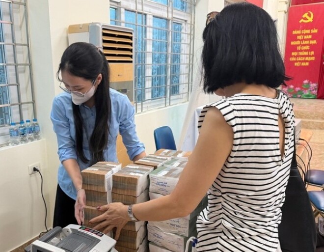 Một người dân nhận tiền đền bù ở phường Bạch Mai (Hà Nội).