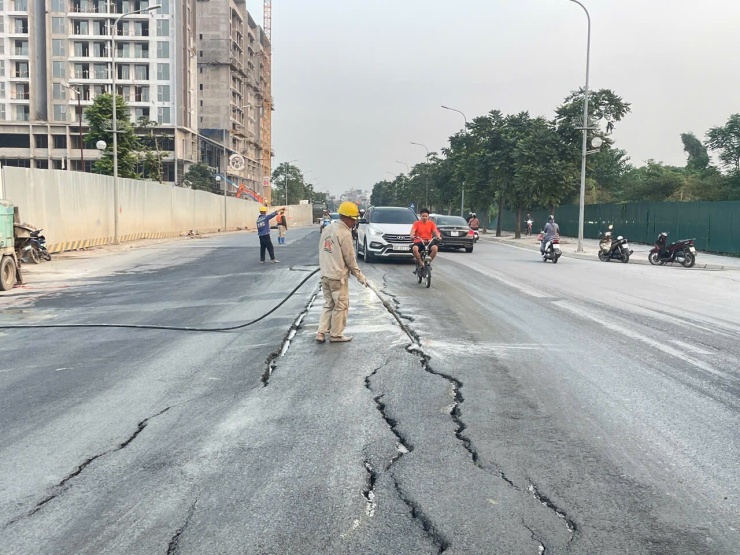 Công nhân bơm ximăng lỏng vào các vết nứt trên đường Vũ Đức Thận, chiều 28/10. Ảnh: Việt An