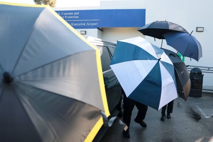 Các sĩ quan cảnh sát dùng ô che chắn khi gia đình ông Bolsonaro rời sân bay ở thành phố Miami. Ảnh: AFP