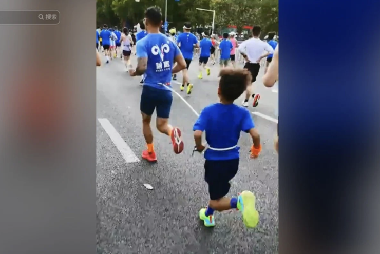 Người đàn ông dùng dây nối với con trai chạy half marathon tại giải Zhengzhou Marathon 2026. Ảnh: Douyin